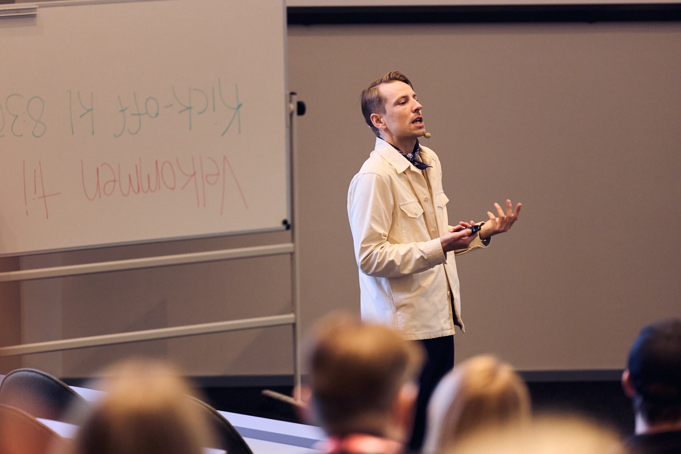 Simon Linde holder oplæg foran en forsamling i et auditorium. Han taler engageret og gestikulerer (på italiensk) med hænderne