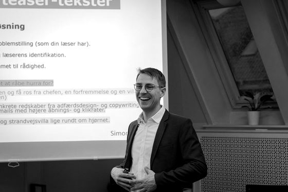 En smilende Simon Linde foran et slide om adfærdsdesign og copywriting